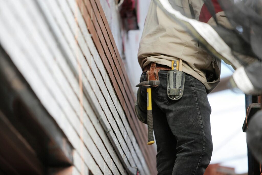 Close-up of a construction worker with hammer and tools, focused on the job.