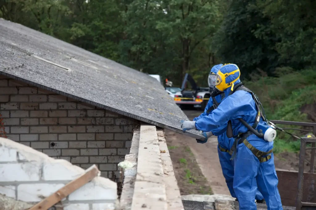 Workers in full protective gear removing asbestos roofing sheets safely in New Zealand.