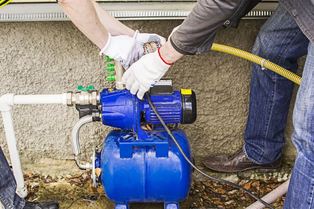 Technicians repairing a blue home water pump system installed in New Zealand.