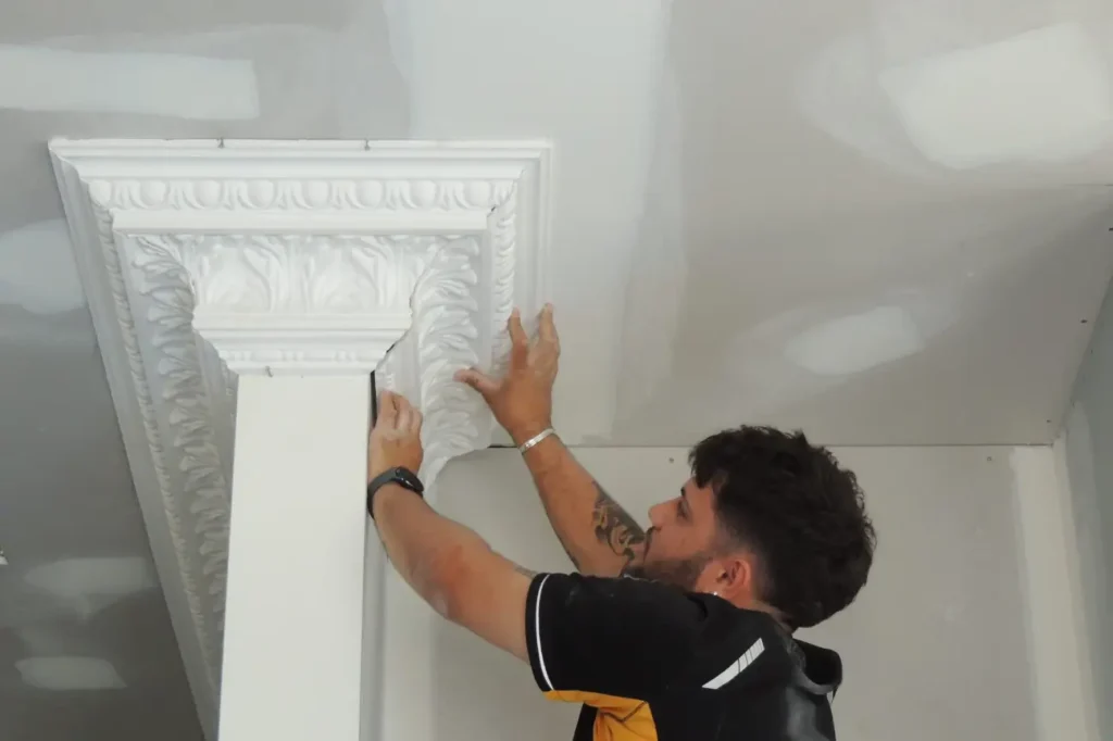 Installing a decorative plaster cornice inside a New Zealand home.