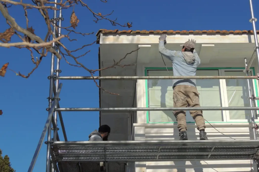 Exterior plastering on a New Zealand home with contractors on scaffolding.