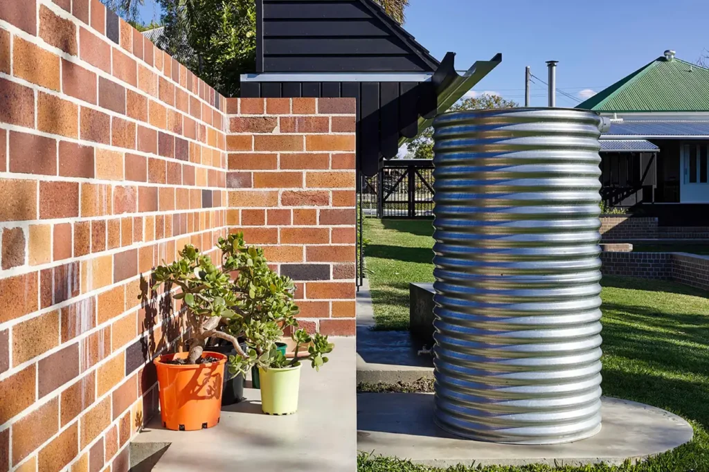 Galvanised outdoor tank beside a brick wall showing Water Tank Installation in New Zealand NZ.