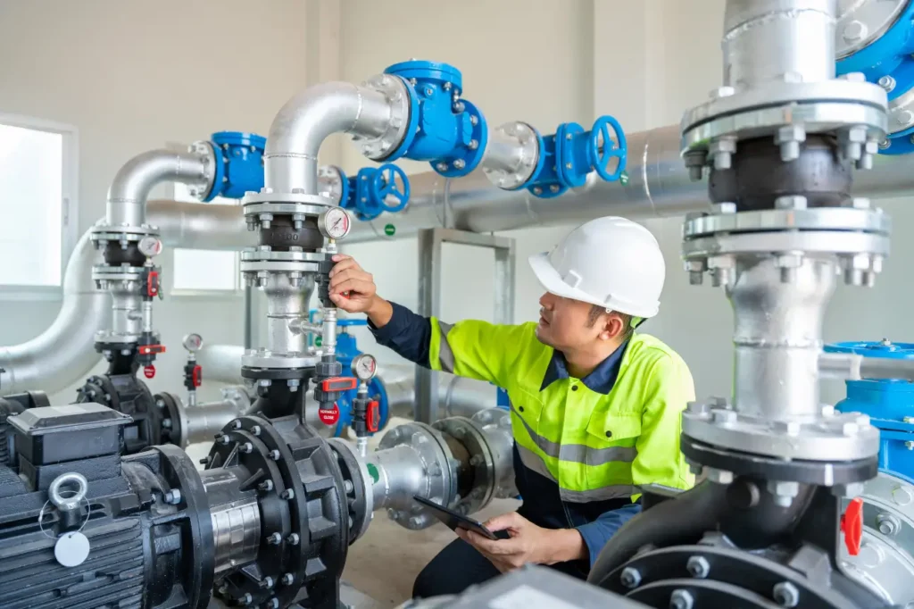 Water pump technician inspecting industrial valve system installed by water pump installers in New Zealand.