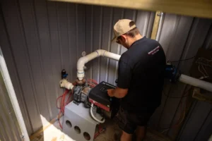 Technician programming a digital water pump unit installed in a New Zealand property.