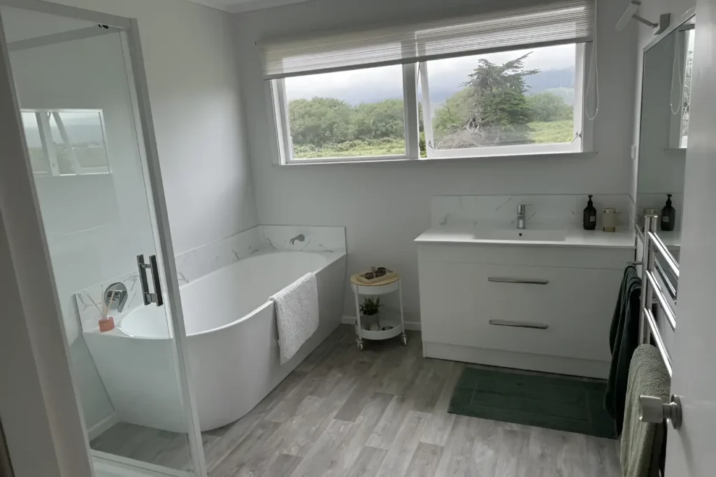 Stylish bathroom in New Zealand featuring a freestanding bathtub, glass shower, and modern vanity highlighting bathroom renovations.