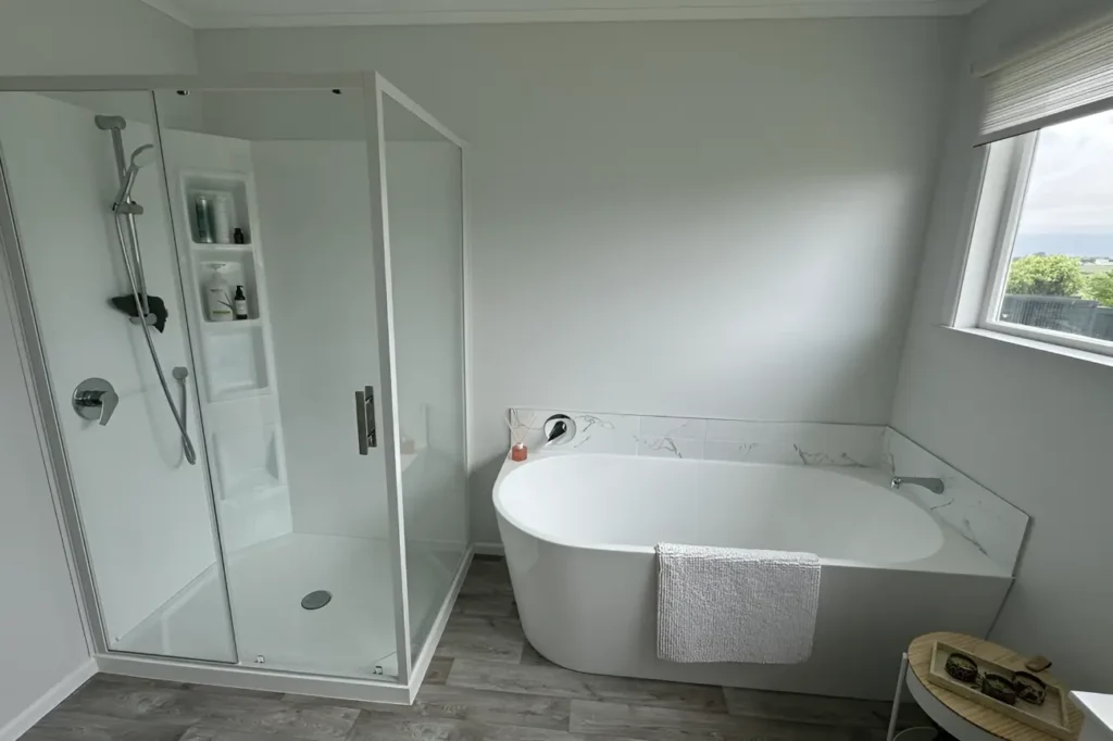 Bright bathroom in New Zealand featuring a glass shower and sleek bathtub showcasing bathroom renovations.