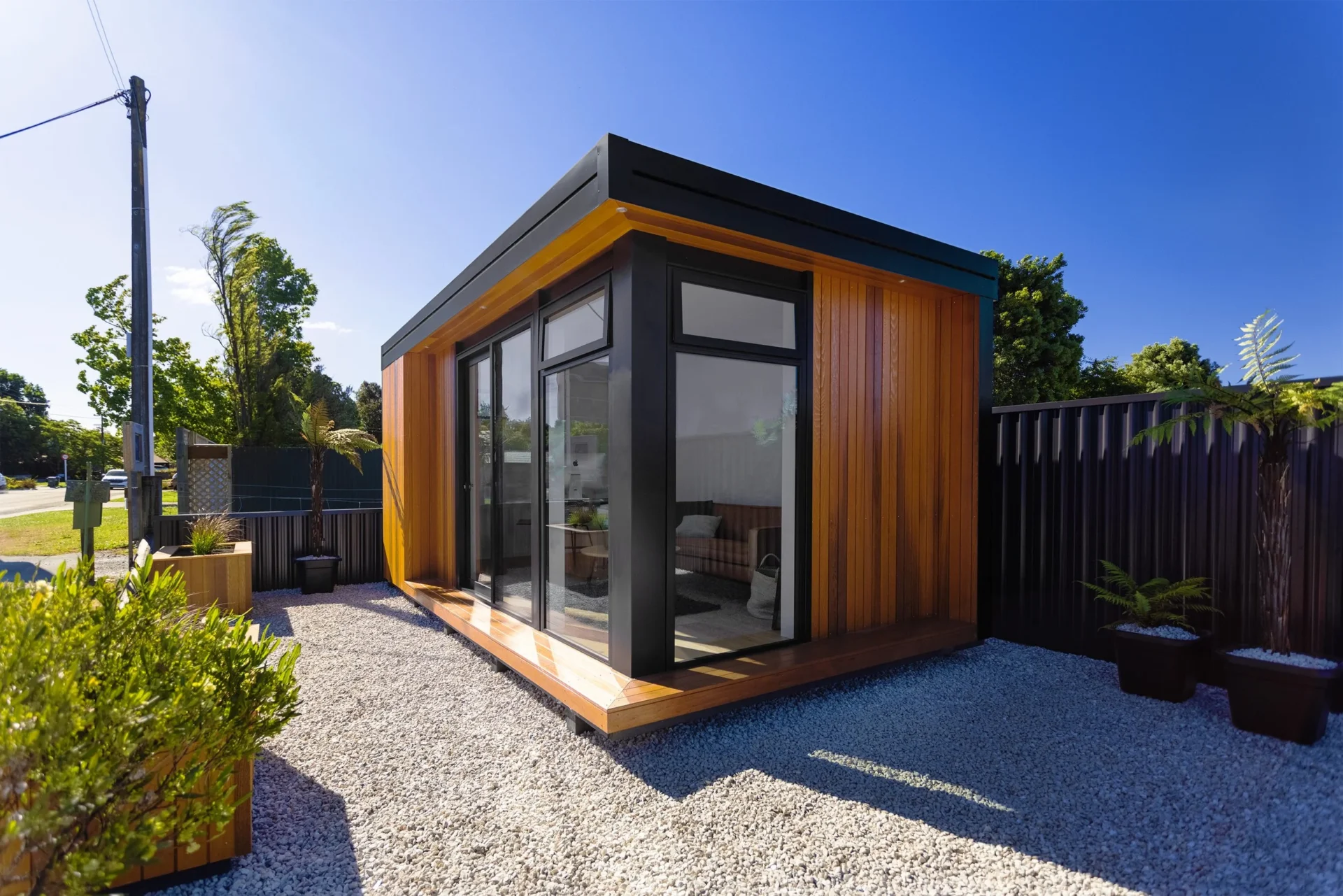 At Tiny Homes New Zealand a contemporary wooden cabin featuring large glass windows and sleek architectural design