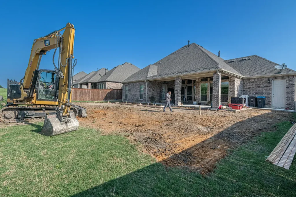 Excavator and worker preparing a residential site for foundation construction, performed by Foundation Contractors New Zealand.