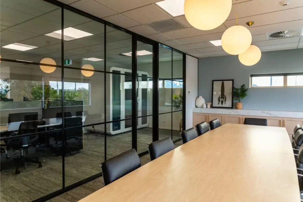 Modern glass-walled meeting room with large boardroom table and pendant lighting in an Office Fit Outs New Zealand project.