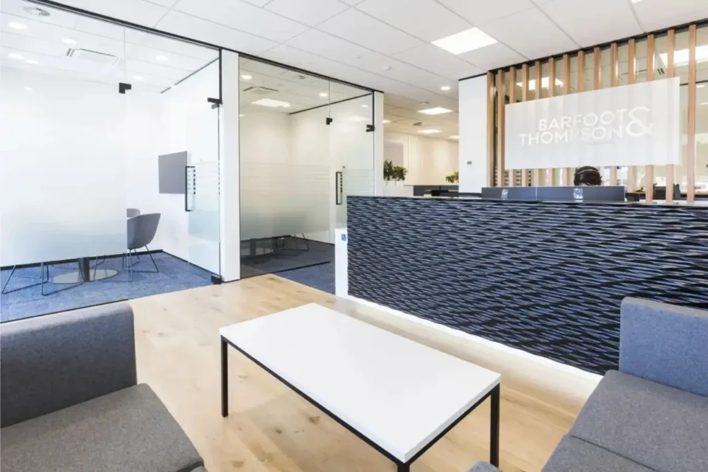 Modern office reception area with glass meeting rooms and textured reception desk in an Office Fit Outs New Zealand project.