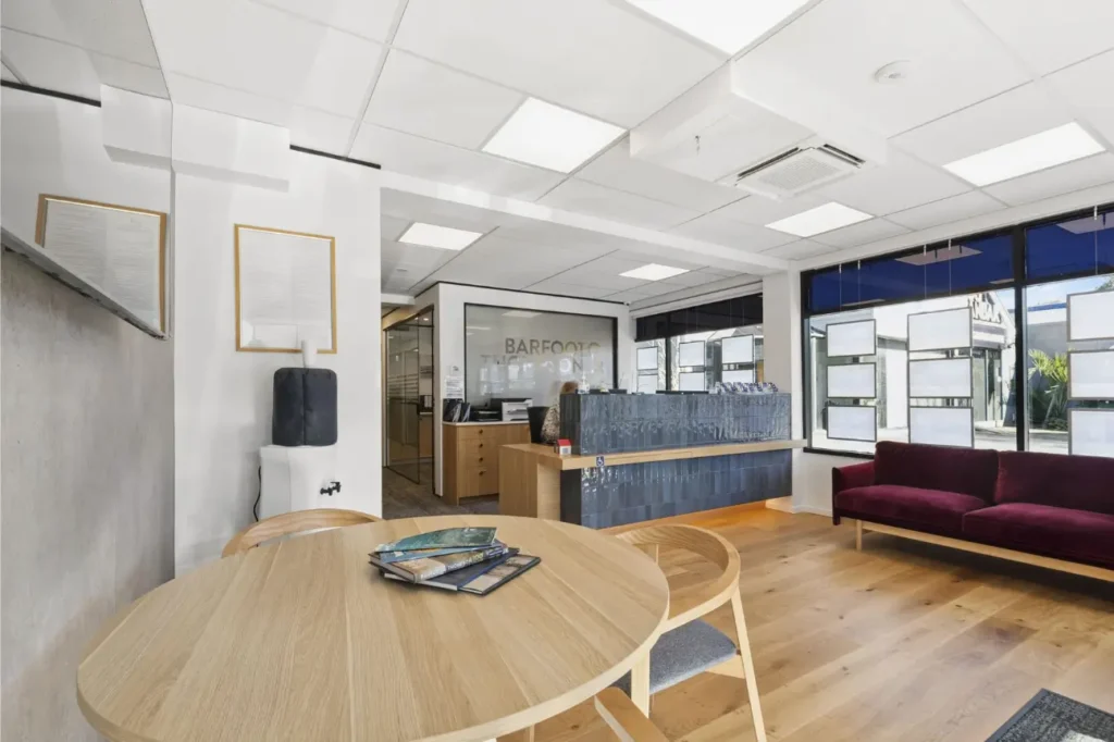 Modern office reception and waiting area with timber flooring, round table, and custom reception desk in an Office Fit Outs New Zealand project.