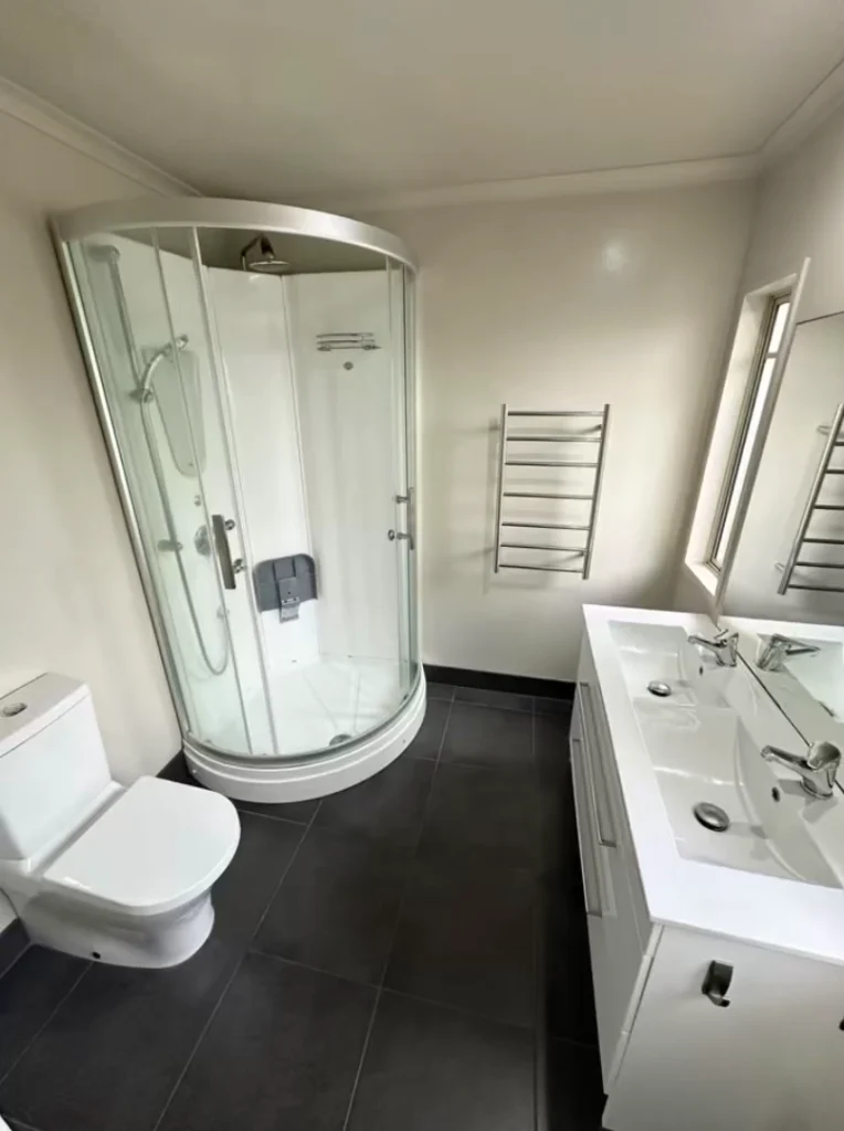 Stylish Bathroom Renovations in New Zealand showcasing a curved glass shower modern vanity and clean contemporary layout.