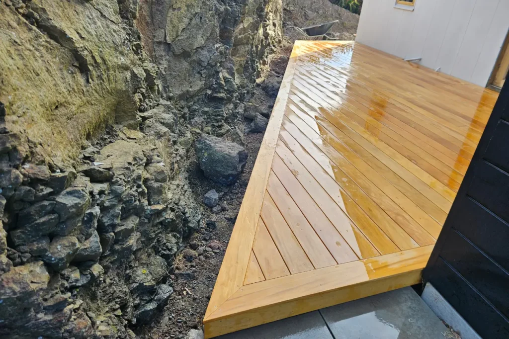 Narrow timber deck installed beside a rock wall by deck builders New Zealand.
