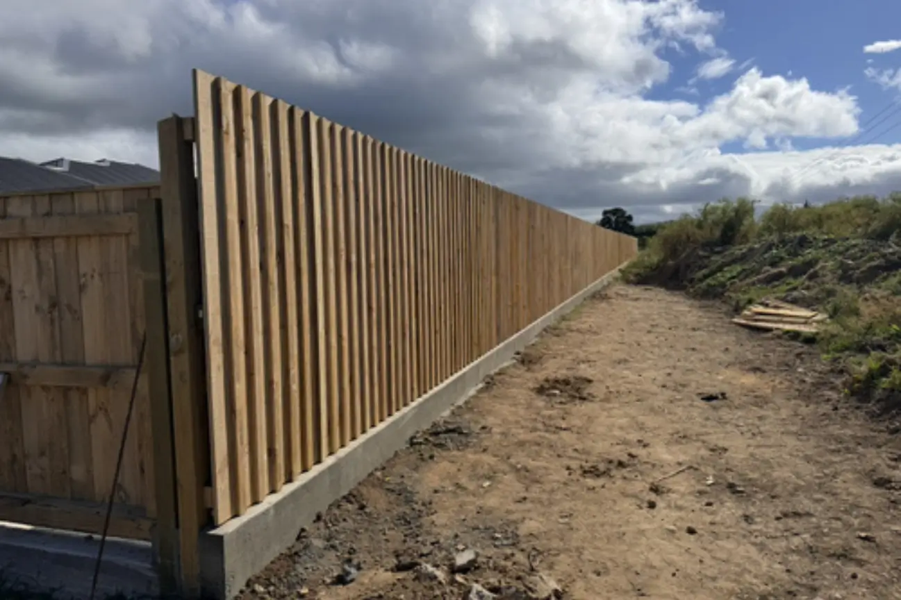 A newly installed timber vertical batten fencing boundary on a concrete base in New Zealand.