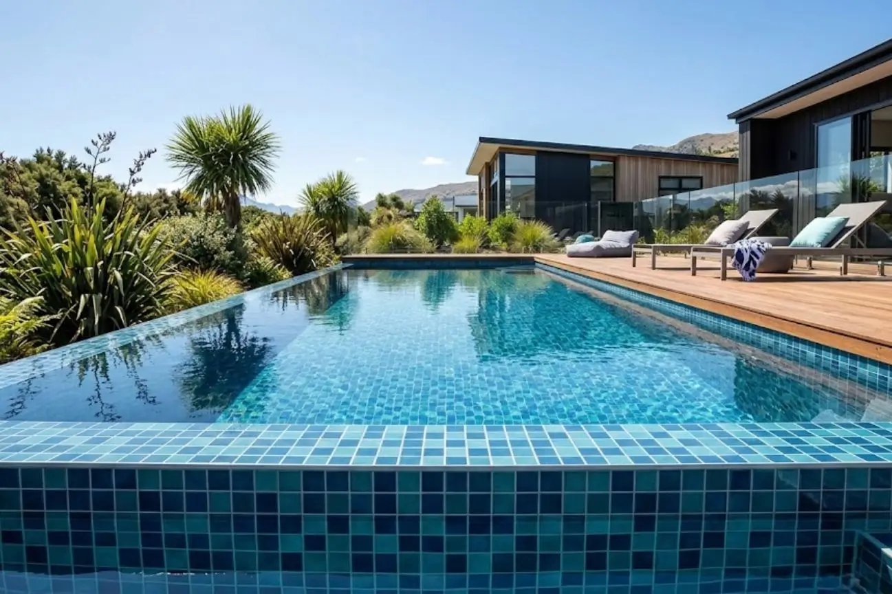 Luxury infinity edge swimming pool with vibrant blue mosaic tiles installed by New Zealand Pool Tiling for our about us page.