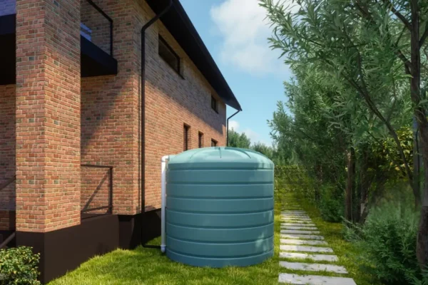 Green water tank beside a brick house showing professional Water Tank Installation in New Zealand NZ.